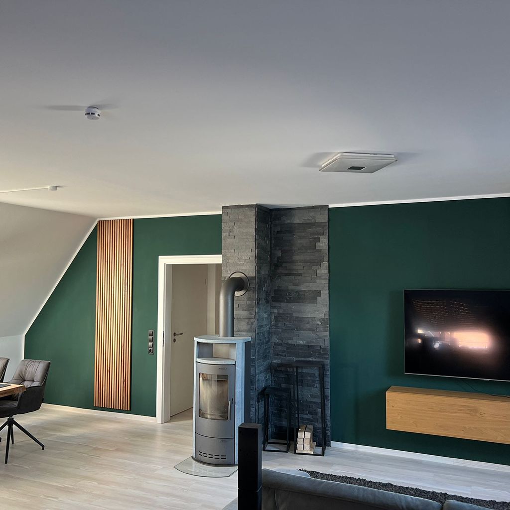 Modernes Wohnzimmer mit grünen Wänden und Holzdetails