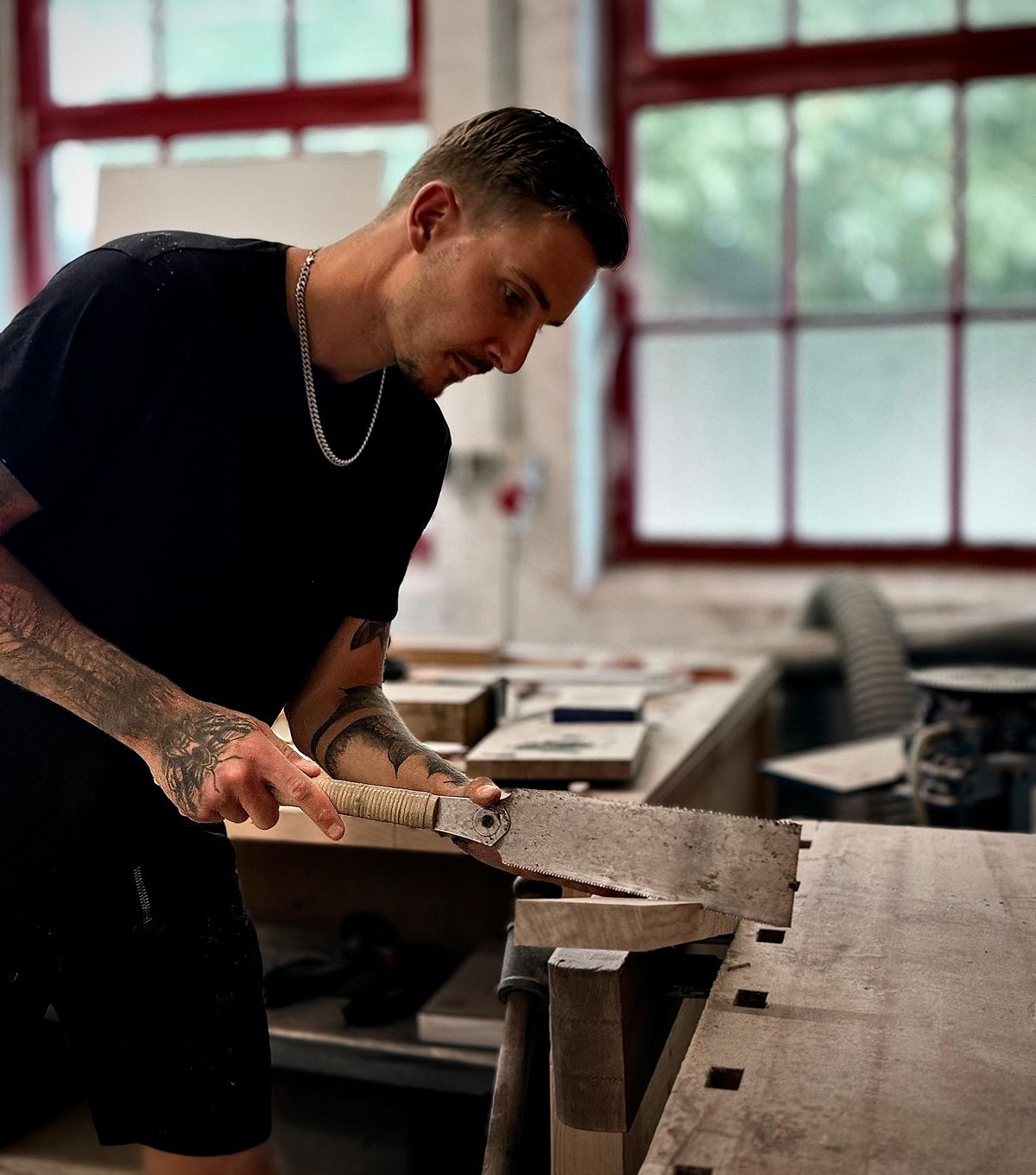 Handwerker, der mit einer Säge Holz bearbeitet.